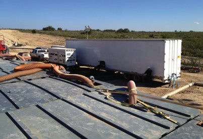 UVX trailer next to a lined frac water pit with transfer hoses